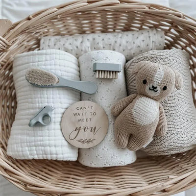 Baby grooming kit in soft blush, featuring soft washcloths, a hairbrush, a nail clipper, and a knitted teddy bear.