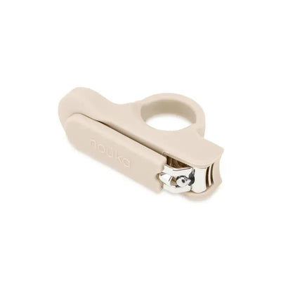 Baby nail clipper by Nouka in a soft beige color with a round handle and silver cutting edge.