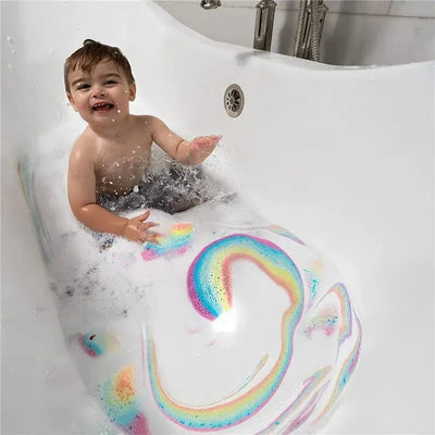 A happy child sits in a bubbly bathtub, playing with colorful foam creating a rainbow pattern in the water.