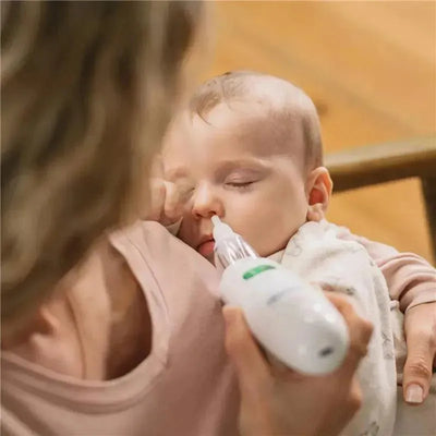 Electric nasal aspirator being used on a sleeping baby, with a parent gently holding the baby.