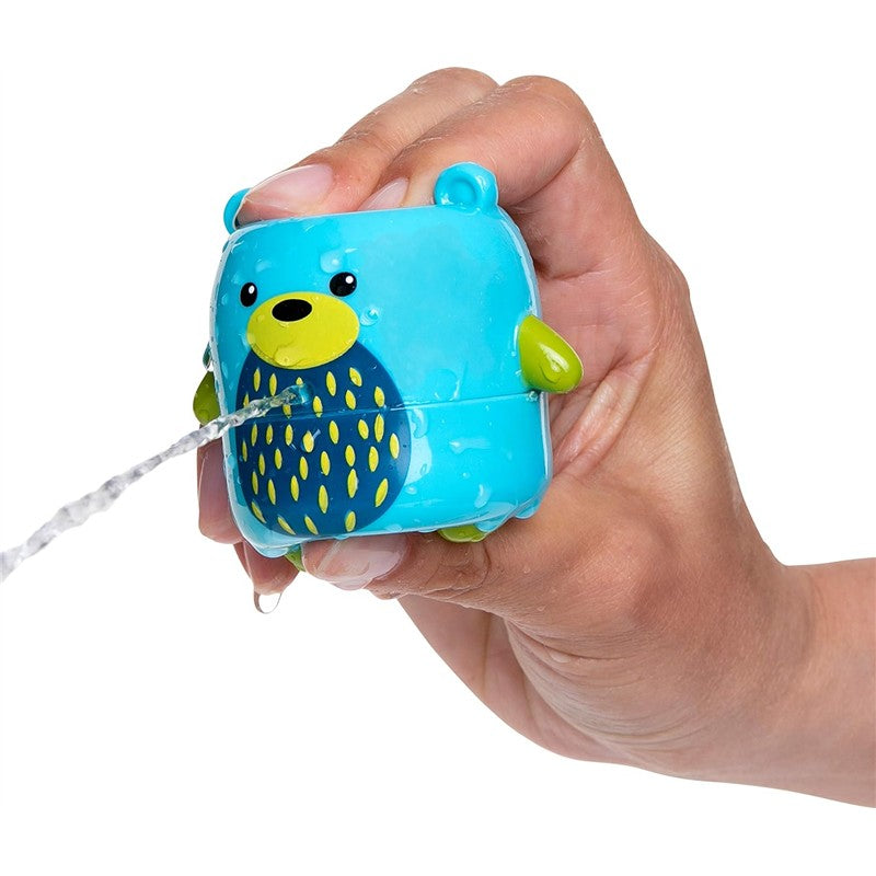 Nuby Silly Squirts Bear bath toy held in a hand, spraying water from its mouth, wet with droplets.