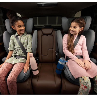 Two young girls sit in a car, each in a Nuna AACE Booster Seat - Caviar, smiling and secured with seat belts.