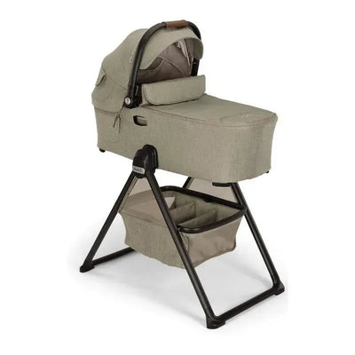 Nuna DEMI™ next Bassinet in Hazelwood color on a stand, featuring a removable canopy and a lower storage basket.