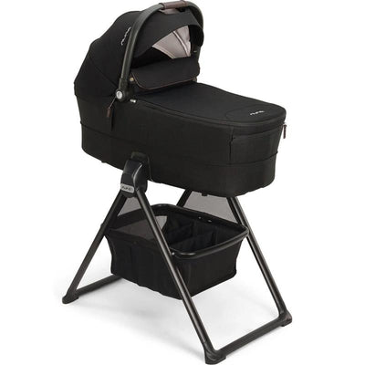 NUNA MIXX Series bassinet in caviar/chocolate color, featuring a sturdy stand and storage basket below.