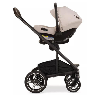 Nuna MIXX™ next stroller with PIPA™ aire rx infant car seat in Biscotti color, featuring a sleek black frame and spacious storage basket.