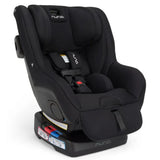Nuna RAVA™ next Convertible Car Seat in Caviar with adjustable straps and safety labels, designed for child safety.