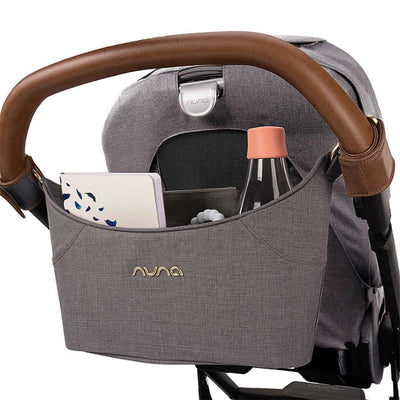 Nuna Stroller Organizer in granite color, featuring a brown handle and pockets for a water bottle, notebook, and baby toy.