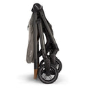 Nuna Swiv + Pipa Aire Rx Travel System in Granite, shown in a folded position, highlighting its compact design and wheels.
