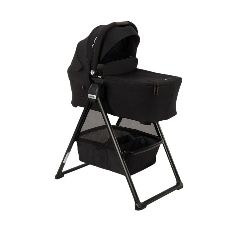 Nuna Swiv stroller with a black bassinet on a black frame, featuring a storage basket underneath.