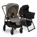 Nuna Swiv stroller with a gray seat and brown handle next to a black bassinet on a stand, showcasing its bundle design.