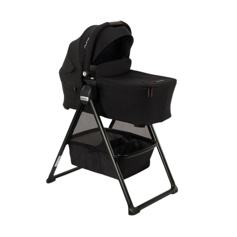 Nuna Swiv Stroller with Swiv Bassinet on a stand, featuring a black fabric design and spacious storage basket.
