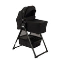 Nuna Swiv Stroller with Swiv Bassinet on a stand, featuring a black fabric design and spacious storage basket.