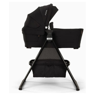 Nuna Swiv™ & Triv™ Series bassinet in caviar with chocolate accents, featuring a sturdy stand and storage mesh.