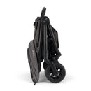 Nuna Trvl 360 Compact Stroller in Pewter, folded and showing its dark fabric and black frame with wheels.