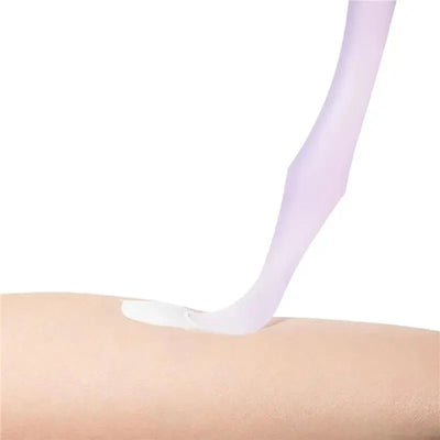 Diaper rash cream applicator in coral color dispensing cream onto a light skin surface.
