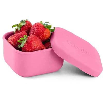 Pink OmieBox food storage container with lid, filled with fresh strawberries, showcasing its sleek design.