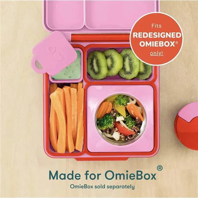 Two pink and teal leakproof dip containers are shown in a colorful lunchbox filled with veggies, fruits, and dip.