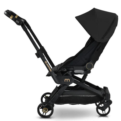 Compact black Orbit Baby M+ stroller with a large canopy, adjustable seat, and gold accents, shown from the side.