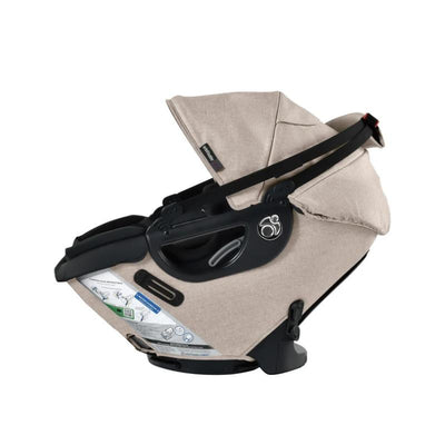 Orbit Baby G5+ rotating infant car seat in Mélange Flax with protective canopy and safety features visible.