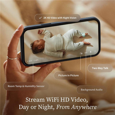Hand holding a smartphone displaying a baby sleeping, with features like 2K HD video, night vision, and room temperature readings.