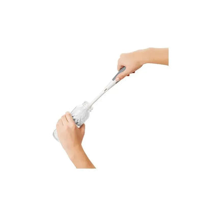 User is cleaning a baby bottle using the OXO Tot Bottle Brush with Bristle Cleaner, showcasing its effectiveness.