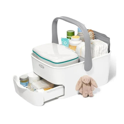 Oxo Tot Diaper Caddy in white and gray, featuring a removable changing mat, storage for diapers, creams, and a soft bunny toy.