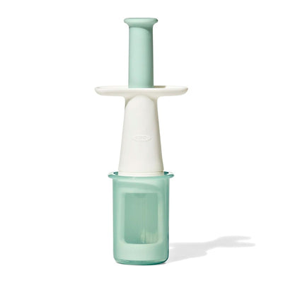 OXO Tot Grape Cutter in opal color with a green container and white handle for cutting grapes safely and easily.