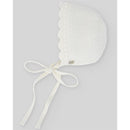 Baby knit bonnet in chalk pink with scalloped edges, ties under the chin, and a button detail on the side.