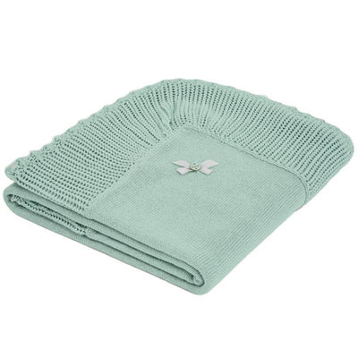 Paz Rodriguez Blanket in soft green with a textured border and a decorative ribbon detail. Perfect for cozying up.