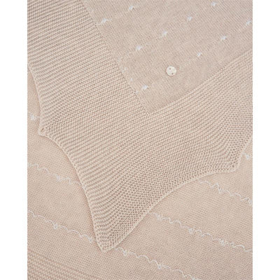 Nectar linen and white blanket by Paz Rodriguez featuring a textured design and decorative button detail.