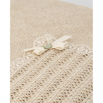 Light brown knit newborn shawl by Paz Rodriguez, featuring a floral lace trim and a decorative bow with a button.