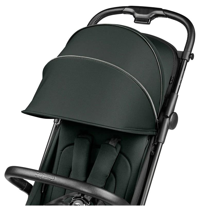 Compact Peg Volo stroller in sage green with a folded canopy, featuring a padded seat and adjustable harness.