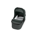Sage green Peg Perego Ypsi bassinet with a metal frame, featuring a soft white interior and a foldable canopy.