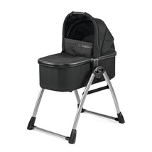 Peg Perego Ypsi Bassinet in True Black on a stand; features a soft hood and sturdy metallic frame.