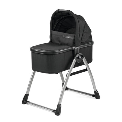 Peg Perego Ypsi Bassinet in True Black on a stand; features a soft hood and sturdy metallic frame.