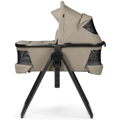 Peg Ypsi Bassinet with Stand By Me in Vanilla Blend, featuring a beige fabric and a sturdy black frame, designed for infants.