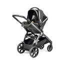 Peg Perego Ypsi Travel System in Vanilla Blend features a sleek design with a car seat attached to a stroller frame and large wheels.