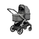 Peg Perego Ypsi Travel System in Vanilla Blend features a gray stroller frame with a bassinet on top, sleek black wheels, and a storage basket underneath.