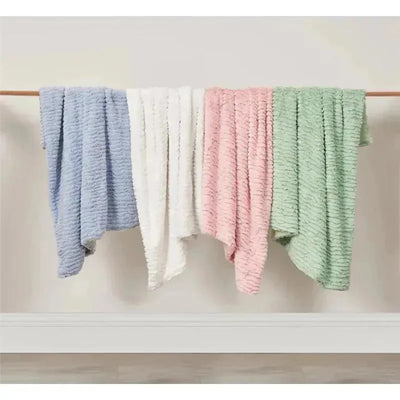 Textured faux fur stroller blankets in pink, blue, white, and green, draped over a wooden hanger.