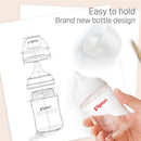 Wide neck Pigeon baby bottle in hand, featuring a clear design, with a sketch of its ergonomic shape on paper.