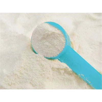 Blue measuring scoop filled with white powder, resting on a bed of the same powder.