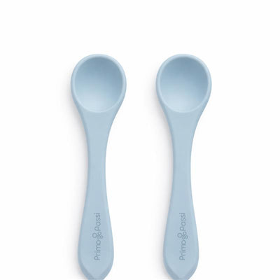 Two Primo Passi silicone spoons in dusty blue, featuring a rounded bowl and ergonomic handle design.