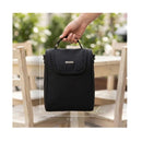 Primo Passi Black diaper bag displayed being held, showing dimensions 9x7x4 inches against a blurred outdoor background.