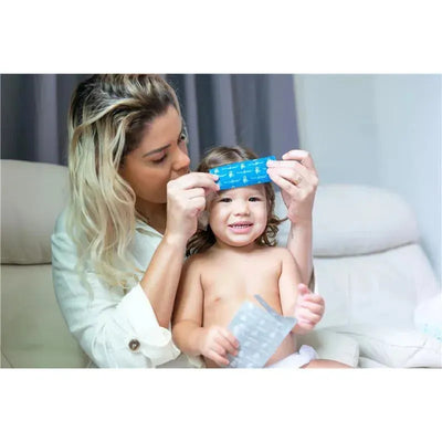 Mother applies a blue Primo Passi Fever Patch to a smiling child, who holds a second patch, in a cozy room setting.