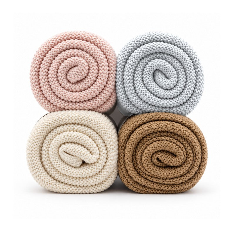 Light pink knit blanket among three other rolled blankets in gray, cream, and brown colors, showcasing soft texture and design.
