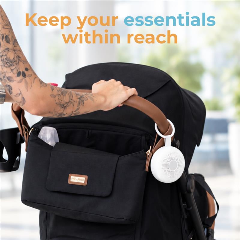 Primo Passi Nero Stroller Organizer attached to a stroller, featuring a front pocket and a white speaker, with a hand reaching for items.