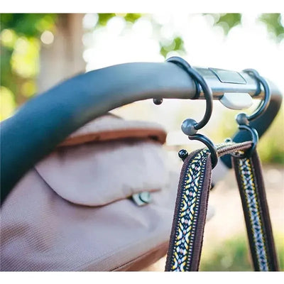 Stroller hooks designed for convenience, featuring a sleek design attached to a stroller handle, holding a decorative strap.