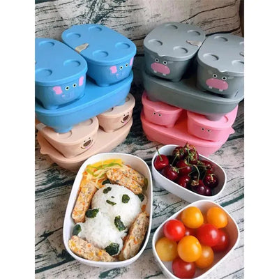Bentomal To-Go containers in elephant and hippo designs, with food including rice, vegetables, cherries, and tomatoes.
