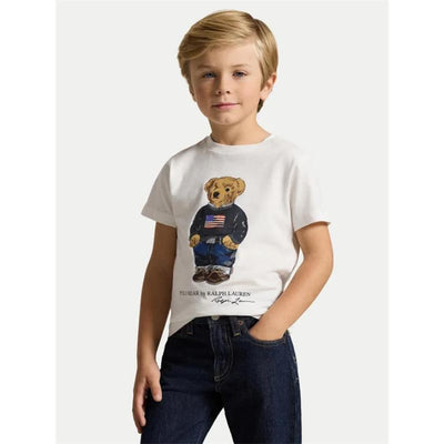 White short-sleeve t-shirt featuring a graphic of a bear in a navy sweater with an American flag, worn by a young boy.