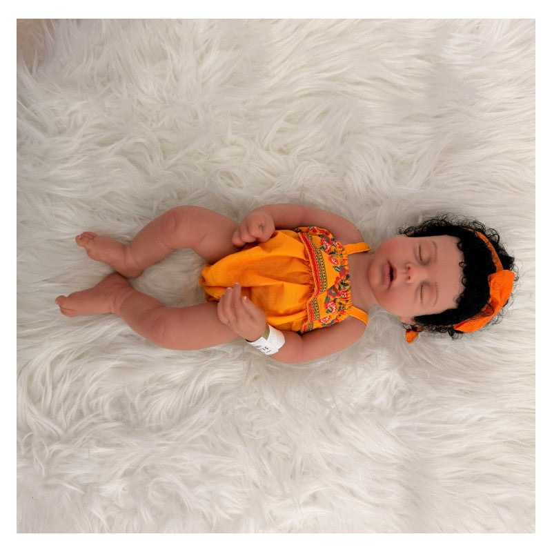 African American full silicone reborn baby doll Arianna, wearing an orange dress with floral designs and a matching headband.